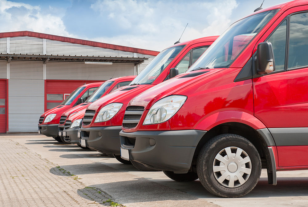 fleet of red vans outside of a garage