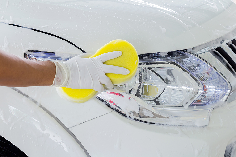 close up person scrubbing car headlight with big sponge