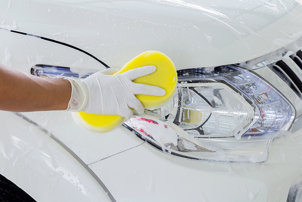 | Schaefer Autobody Centers close up person scrubbing car headlight with big sponge