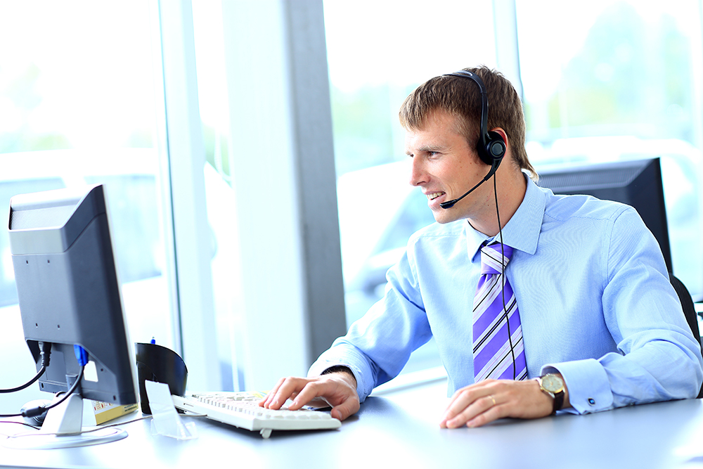 businessperson with headset on looking at computer