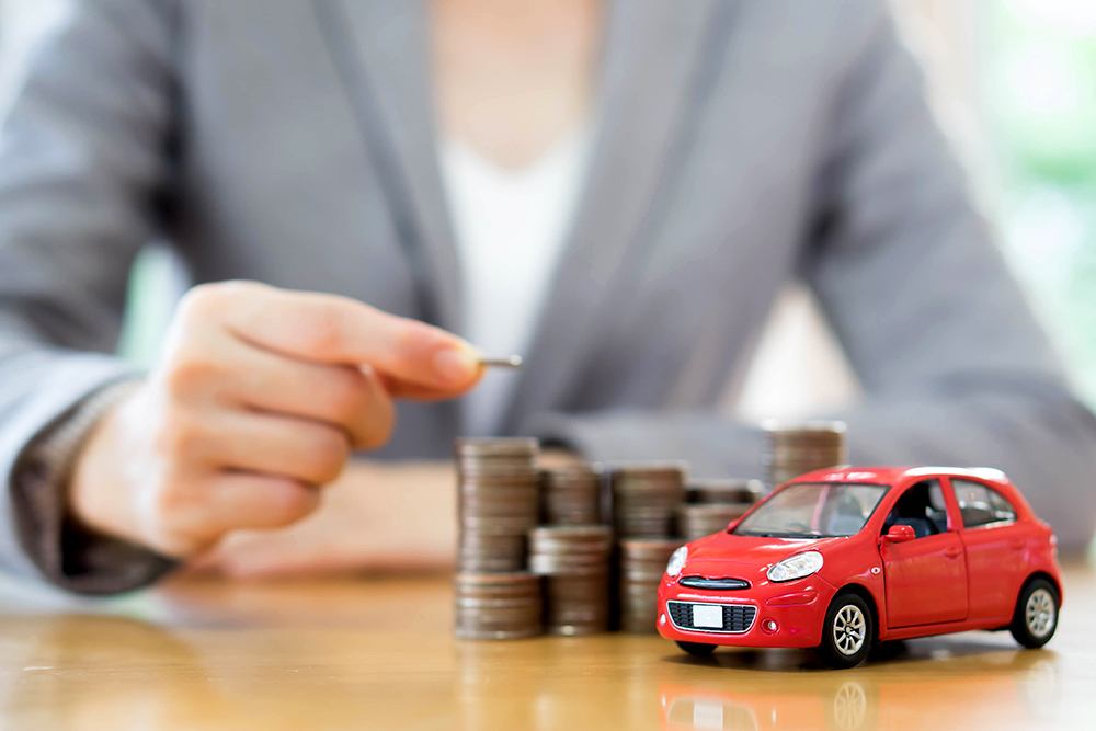 person in blazer stacking change next to toy car