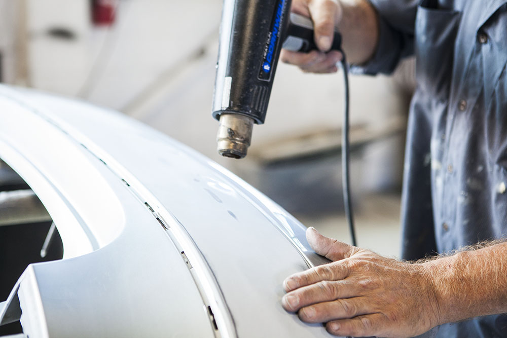 person using tool to repair damaged car