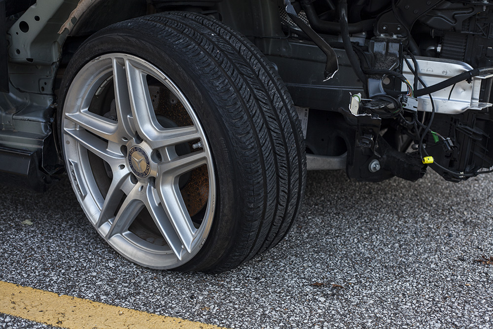 car on road with flat tire and structural damage