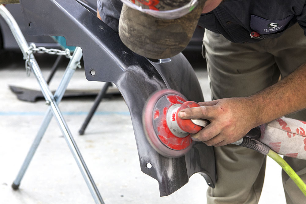 schaefer employee sanding front part of car