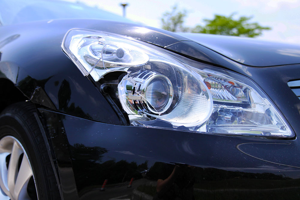 Black car damaged | Schaefer Autobody Centers Headlight and body of a black car damaged in collision