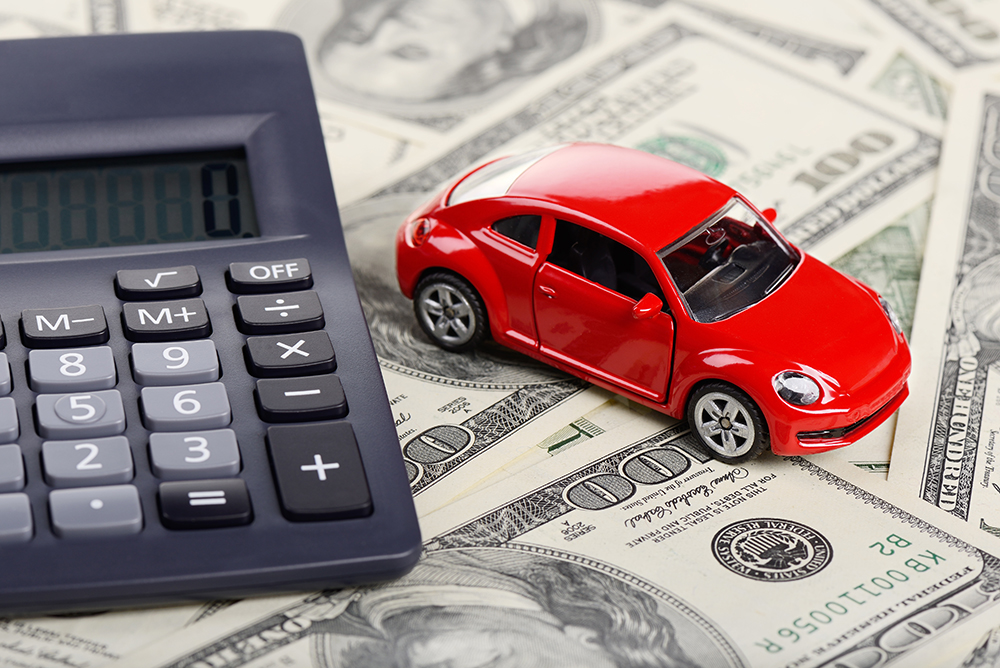Car toy and calculator sitting on dollar bills