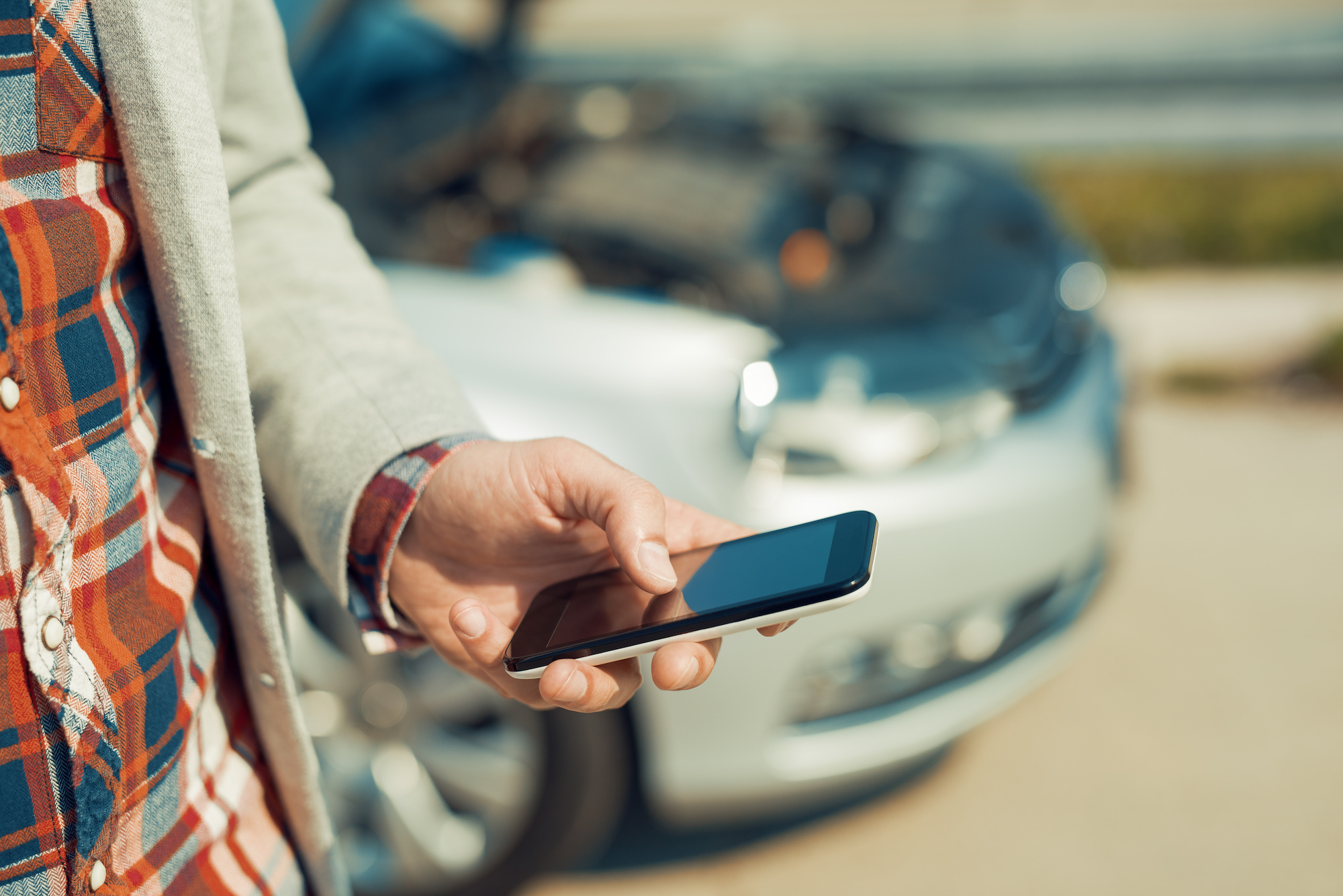 | Schaefer Autobody Centers Man with a silver car that broke down on the road.He is waiting for the technician to arrive.