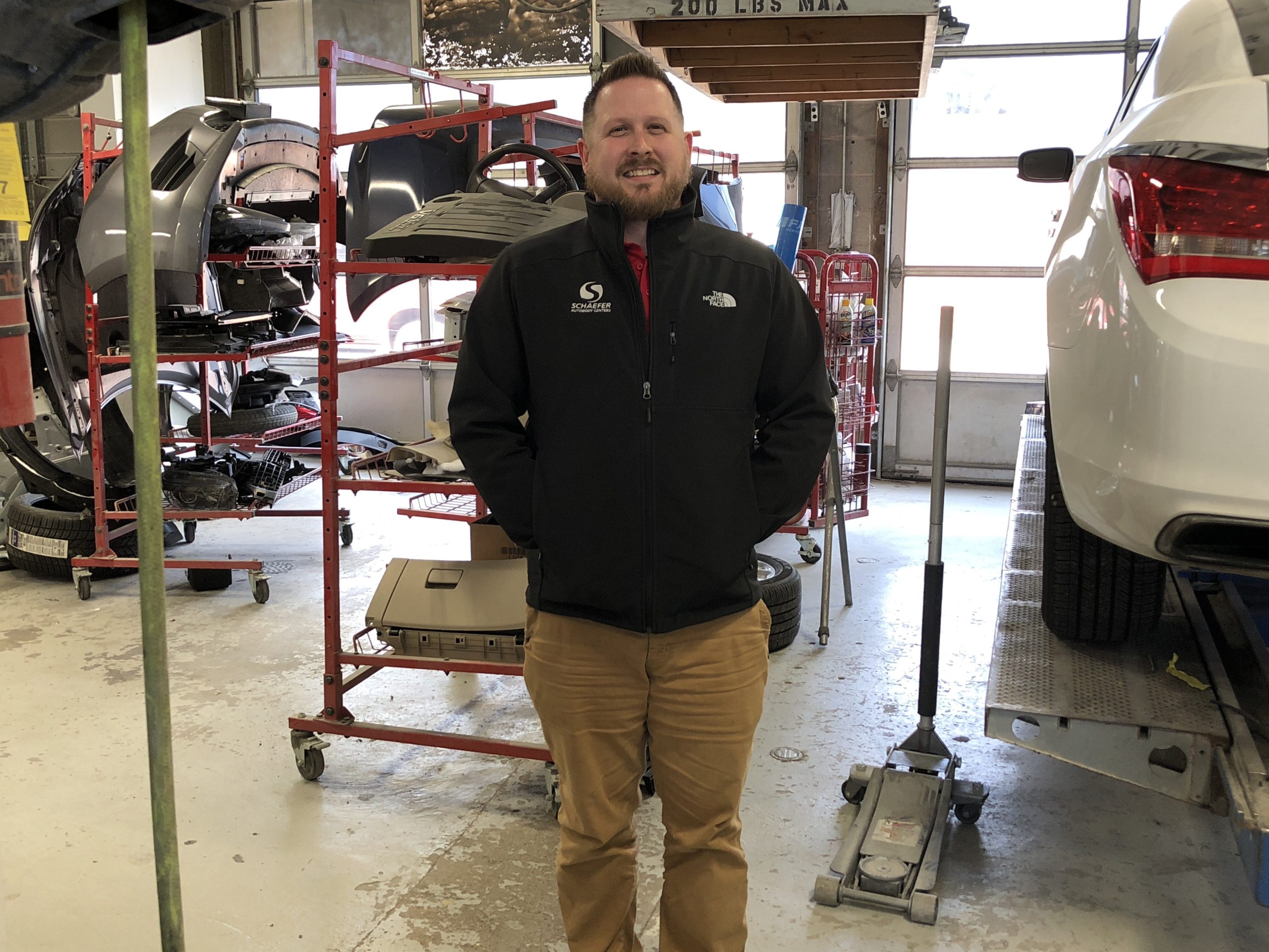 chris standing in repair shop next to lifted car