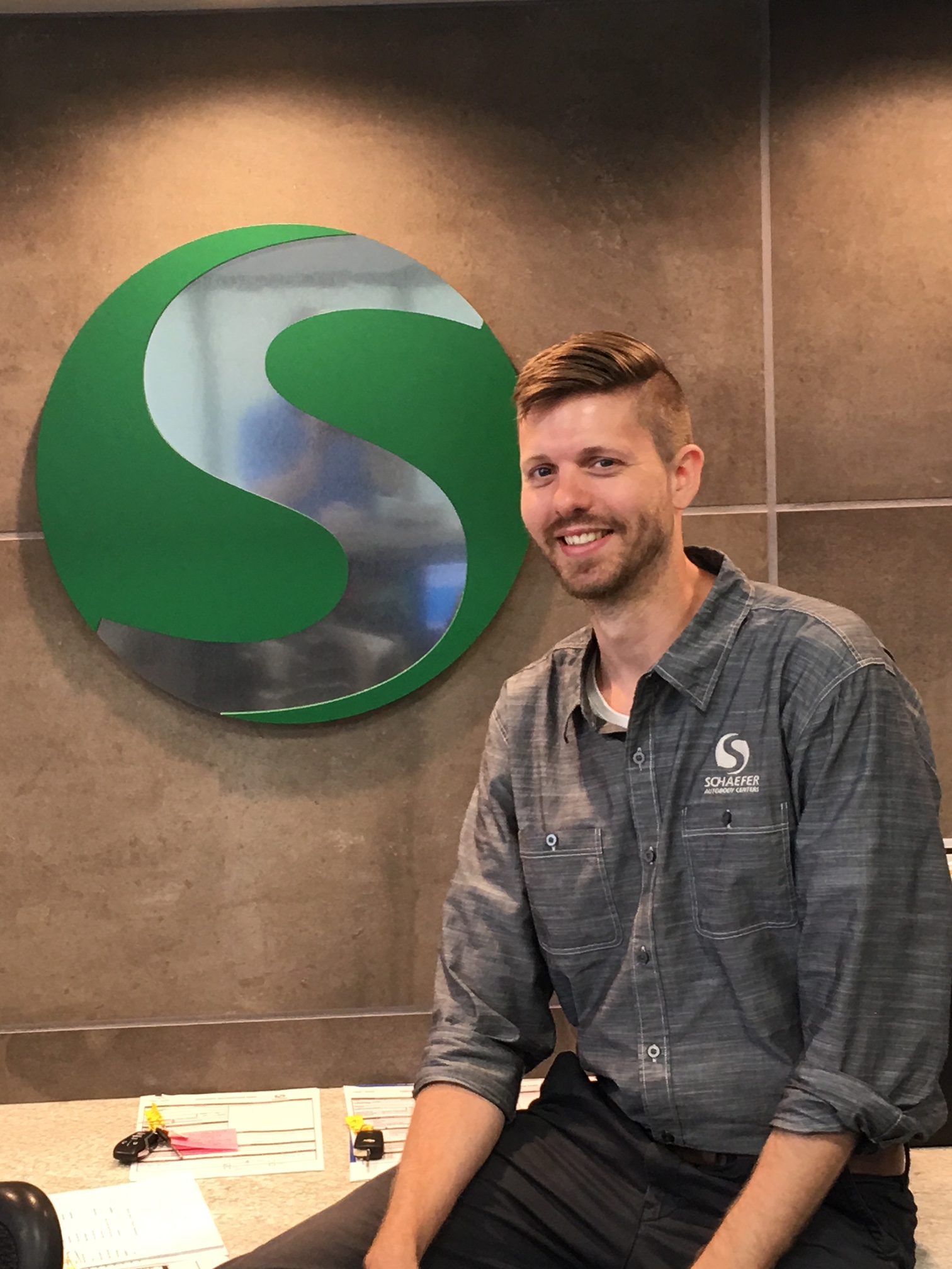 justinhassler-e1528130460724 | Schaefer Autobody Centers justin standing and smiling in front of Schaefer Autobody Centers' front desk