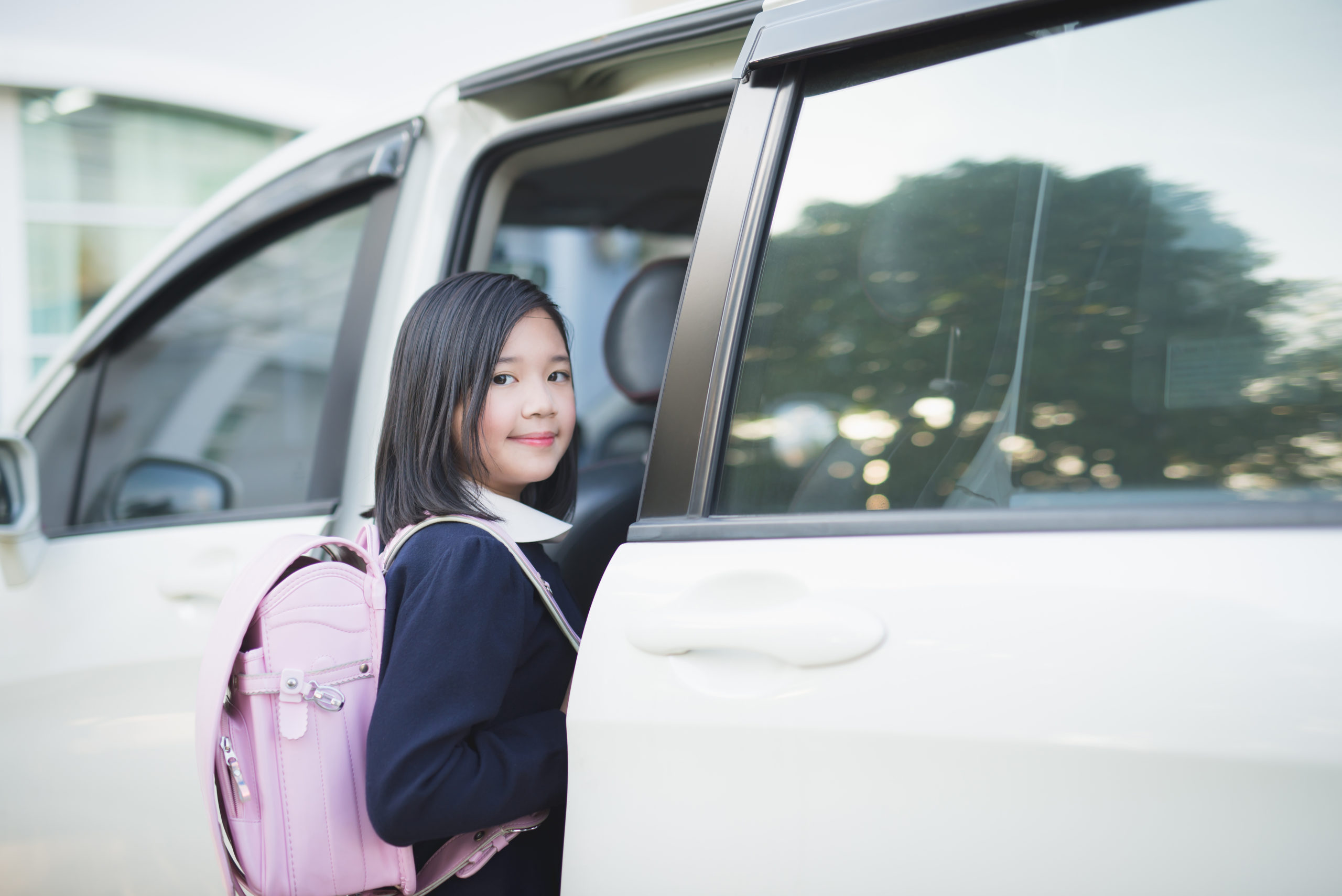 girl in student uniform going to school by car under sunlight