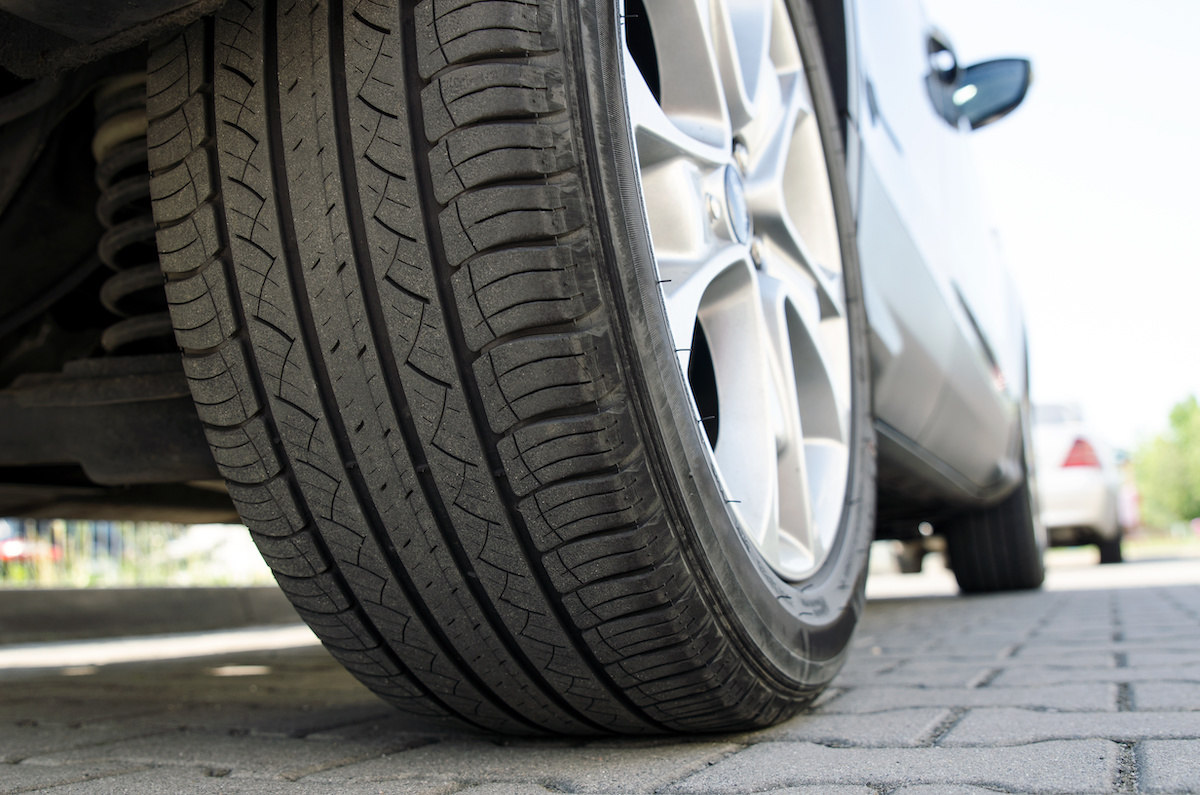 Car all-season tire close up, parked car. Low angle shot, wheel auto with aluminum rim concept