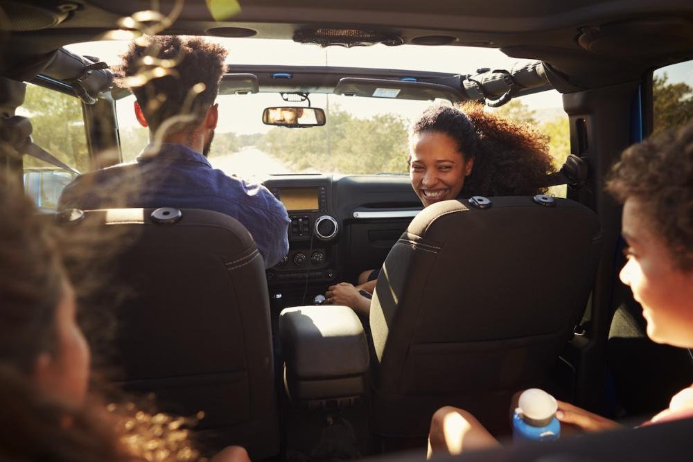 Excited family on a road trip in car, rear passenger POV