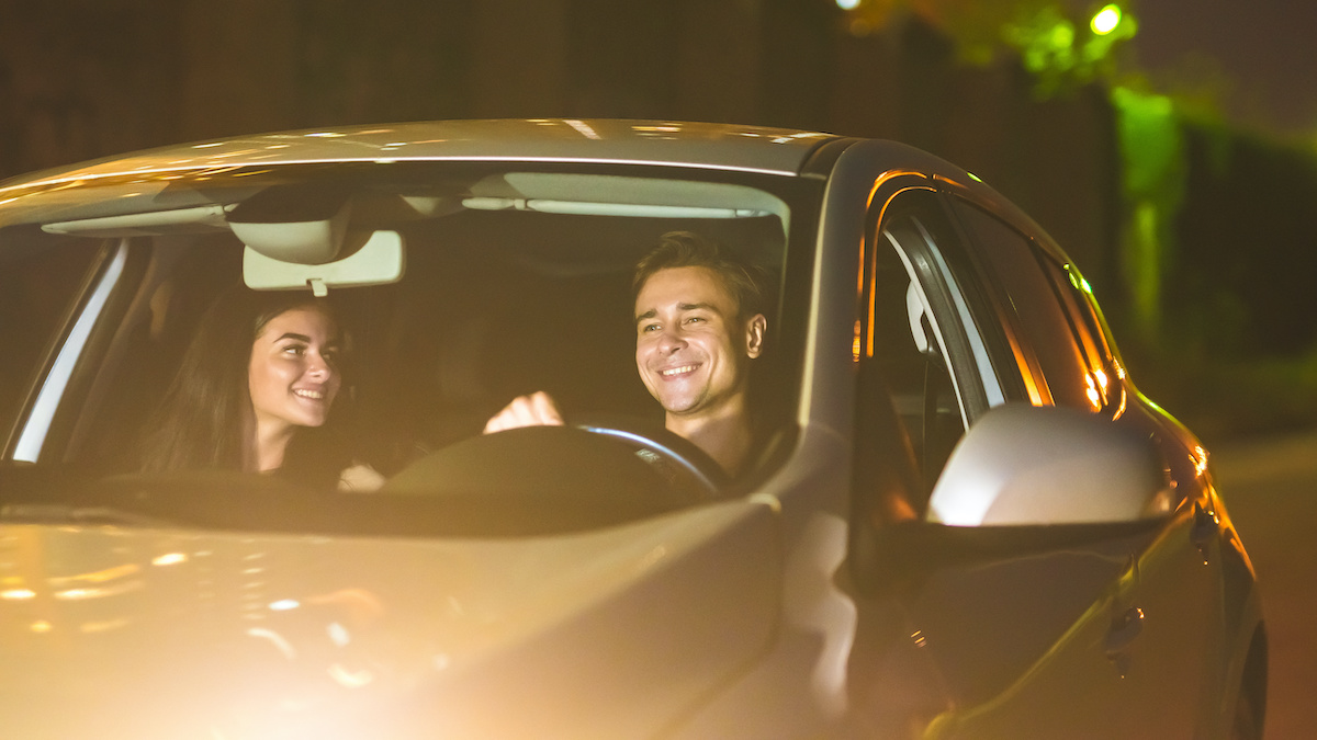 happy man and woman drive a car at night time