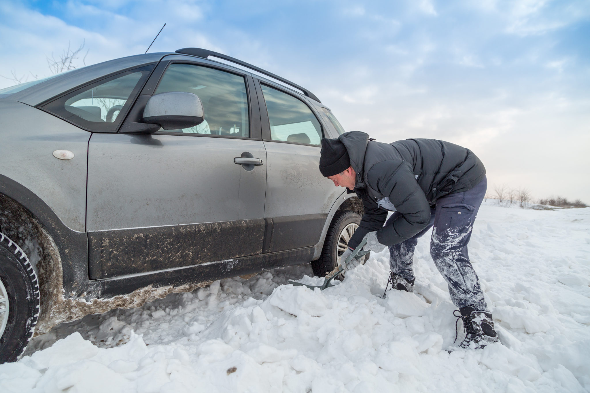 man shoveling snow to free his stuck car