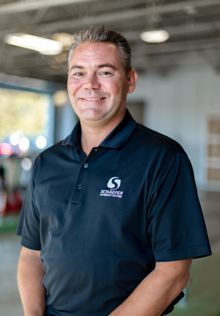 Scott Schaefer, owner of Schaefer Autobody, smiling in Schaefer polo shirt.