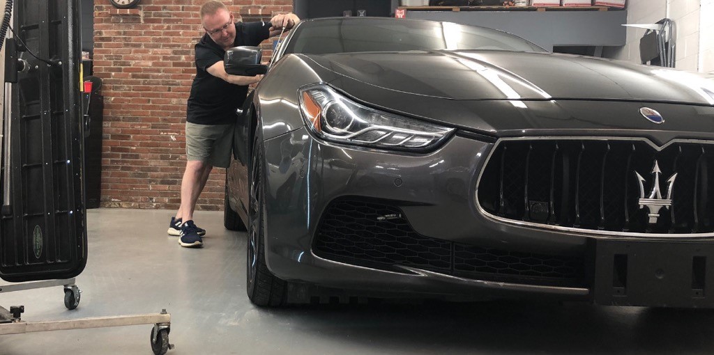 person fixing passenger side window on small gray car