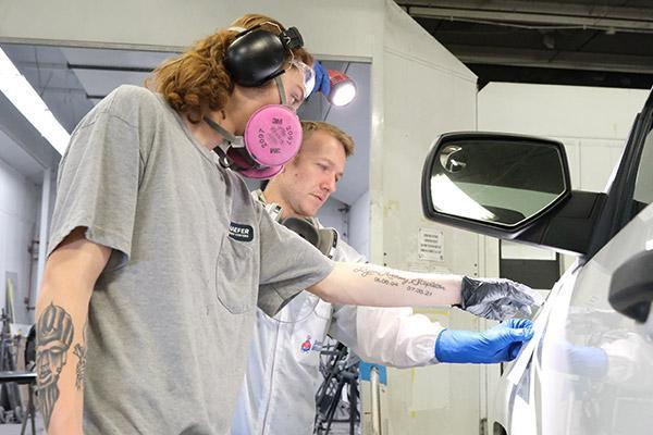 Apprentice and journeyman working together on prepping a car for paint
