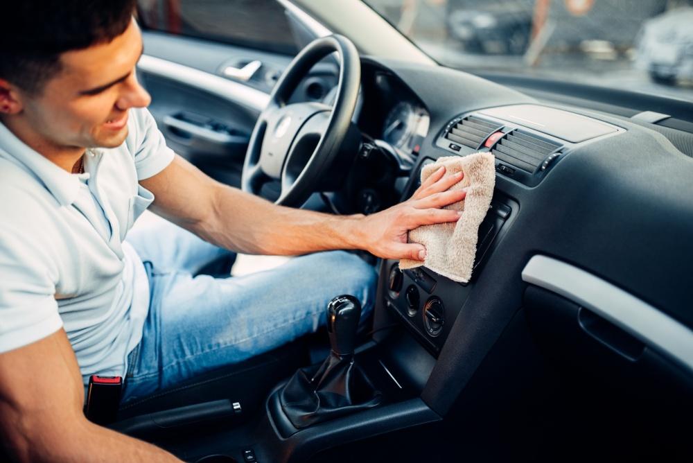 man cleaning inside of vehicle with cleaning cloth