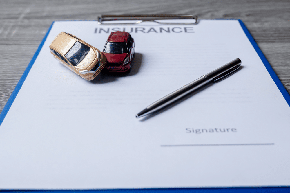 Blog Insurance 2 | Schaefer Autobody Centers insurance paper with a pen and two toy cars in an accident