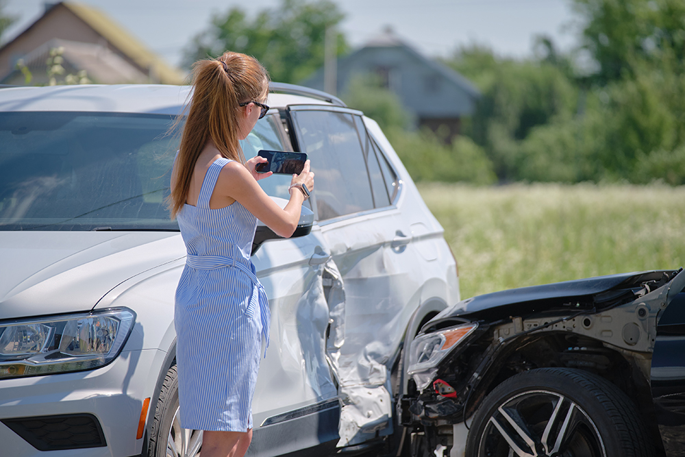 woman taking pictures with her phone of car accident